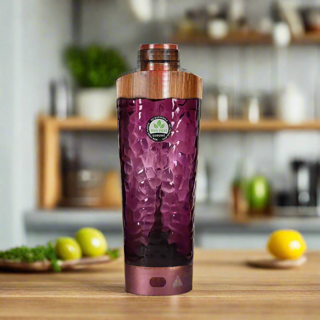 A purple blender with red lid on a pink background with exercise equipment