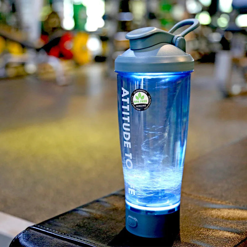 A blue electric protein shaker showing a vortex while mixing a drink on a countertop.