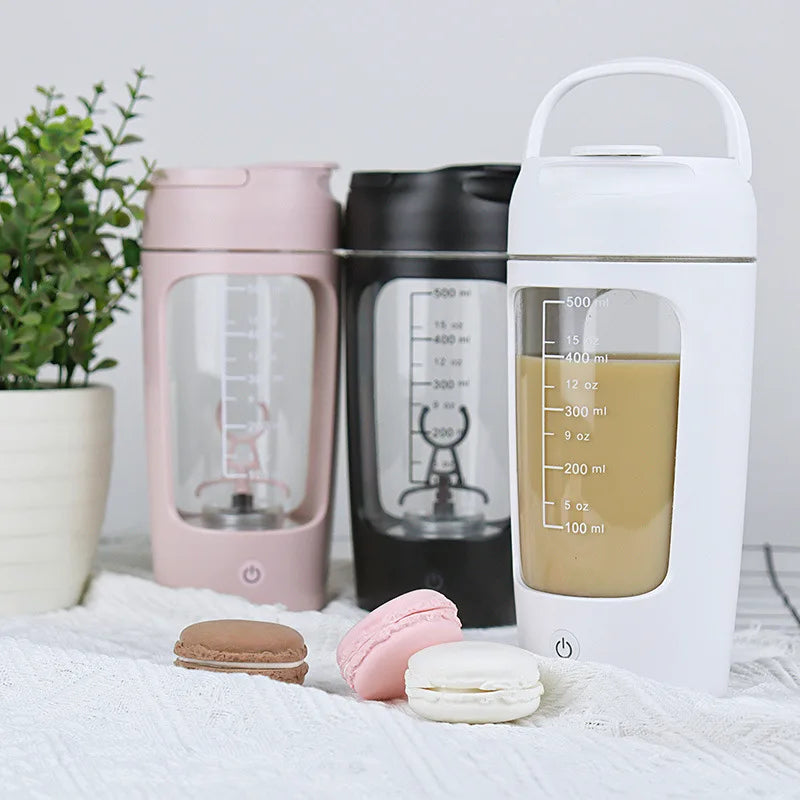 A group of electric protein shaker bottles in assorted colors displayed in a lifestyle kitchen scene.
