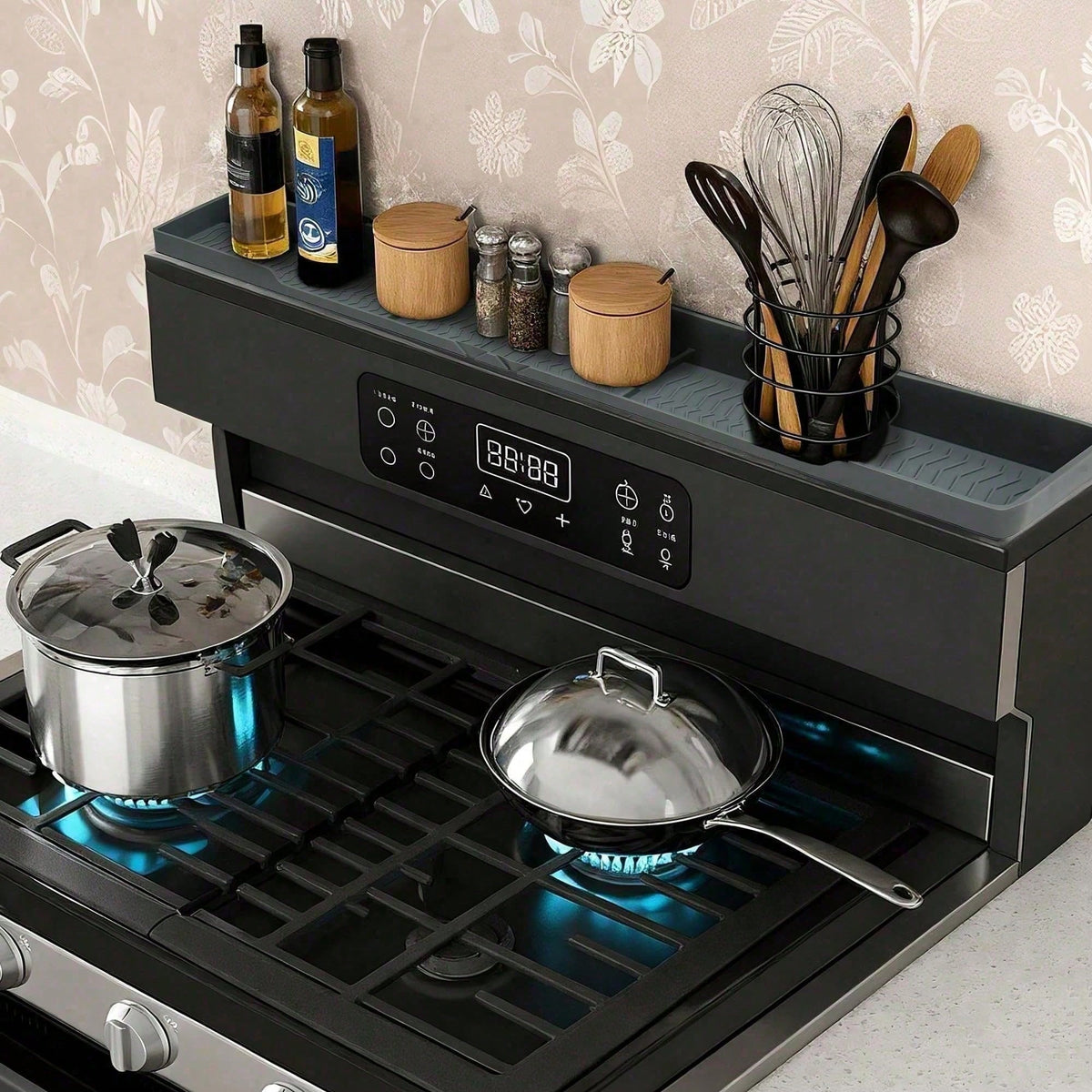 Grey silicone shelf on the back of a stove holding oil bottles, spice jars and a utensil holder