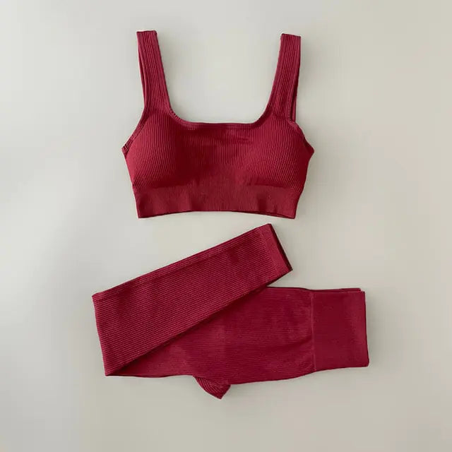 A Red-colored ribbed workout set with sports bra top and high-waisted shorts against light white  background