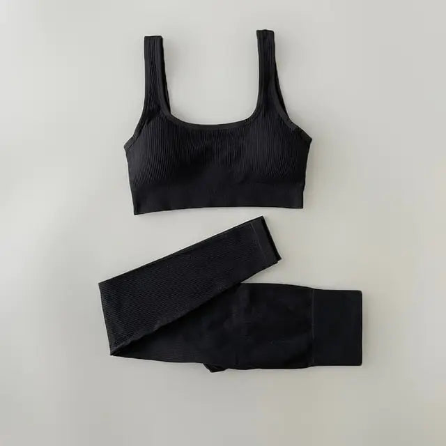 A black-colored ribbed workout set with sports bra top and high-waisted shorts against light white  background