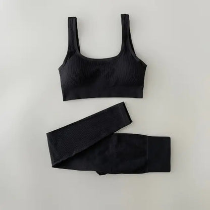 A black-colored ribbed workout set with sports bra top and high-waisted shorts against light white  background