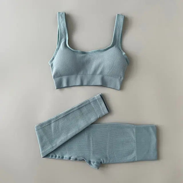 A light blue-colored ribbed workout set with sports bra top and high-waisted shorts against gray background