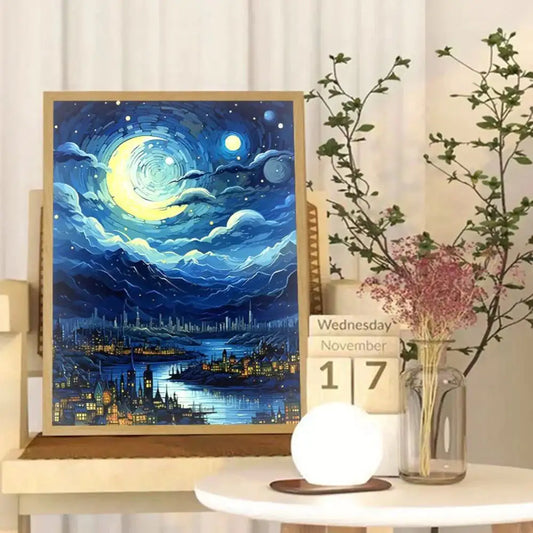 A painting of a stylized night scene with a crescent moon, clouds, cityscape, and mountains, accompanied by a wooden desk calendar and vase in the setting