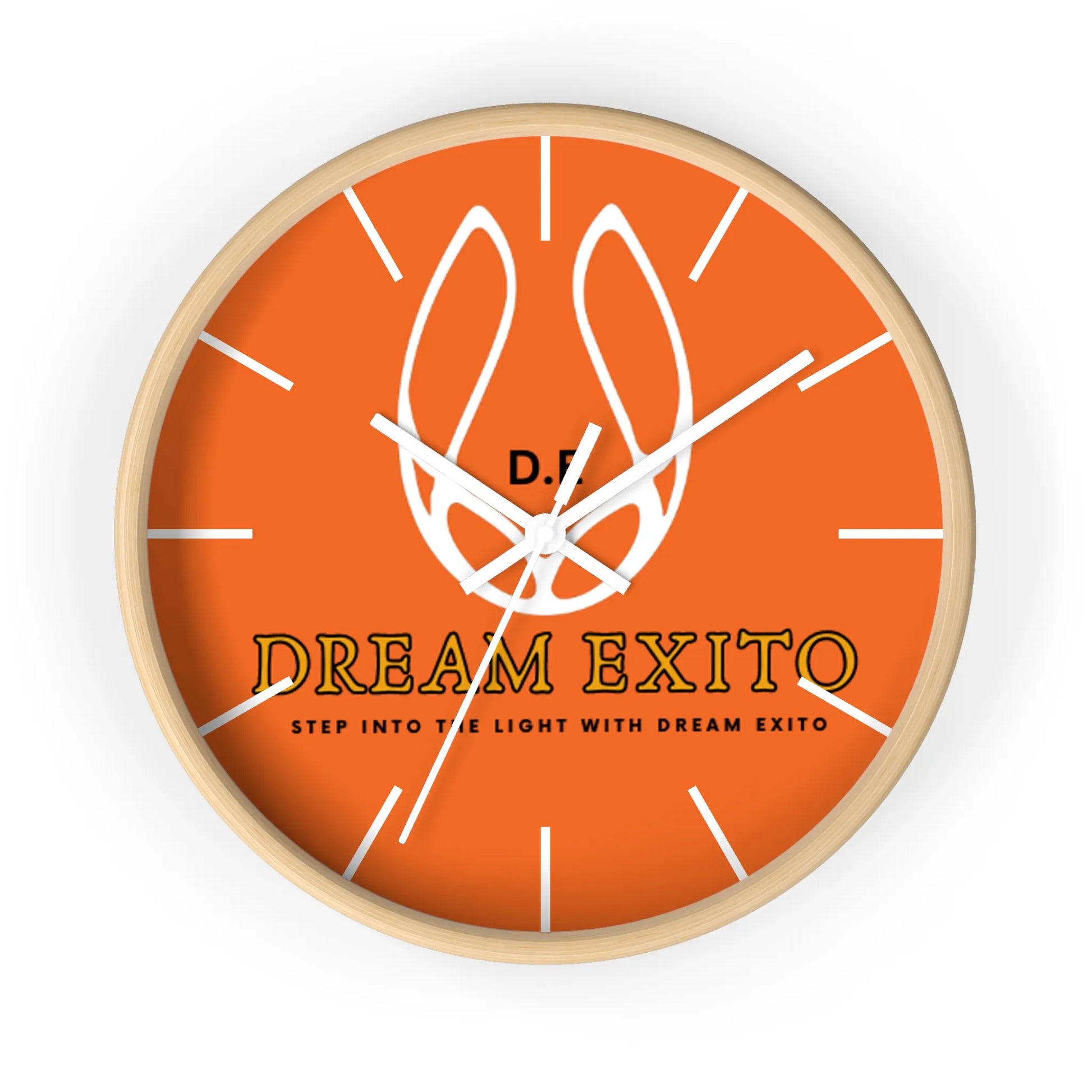 A round wall clock with an orange face, white tick marks, and the text "DREAM EXITO.