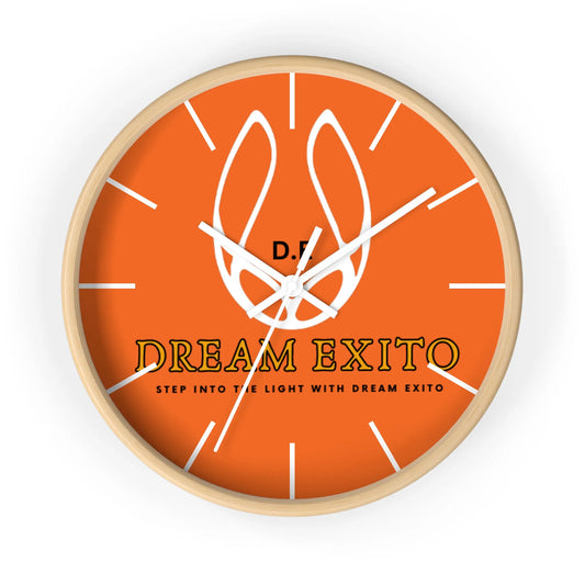 A round wall clock with an orange face, white tick marks, and the text "DREAM EXITO.