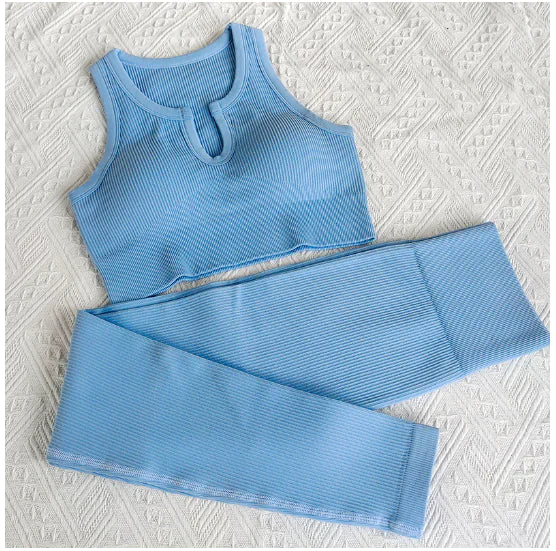 Alight blue-colored ribbed workout set with sports bra top and high-waisted shorts against light white  background