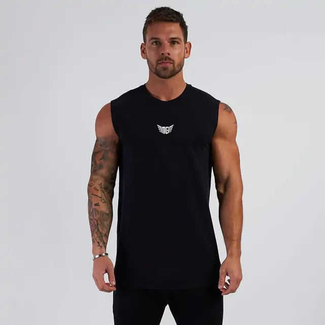 Athletic build man in black sleeveless fitness shirt with white wing logo, arm tattoos, on light background