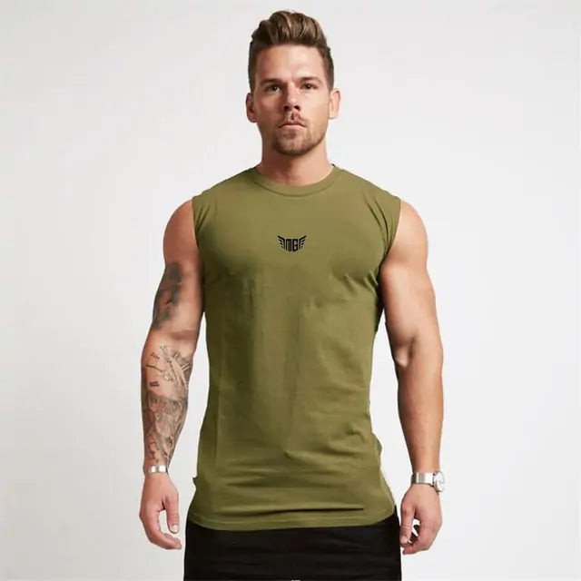 Athletic man in olive green sleeveless shirt with small wing logo, showing tattooed arm against white backdrop.