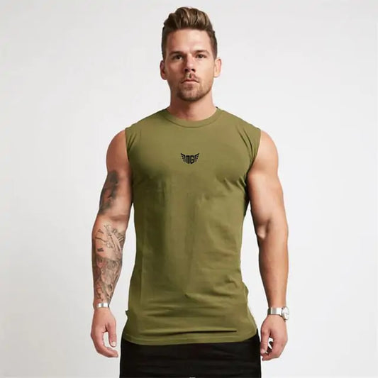 Athletic man in olive green sleeveless shirt with small wing logo, showing tattooed arm against white backdrop.