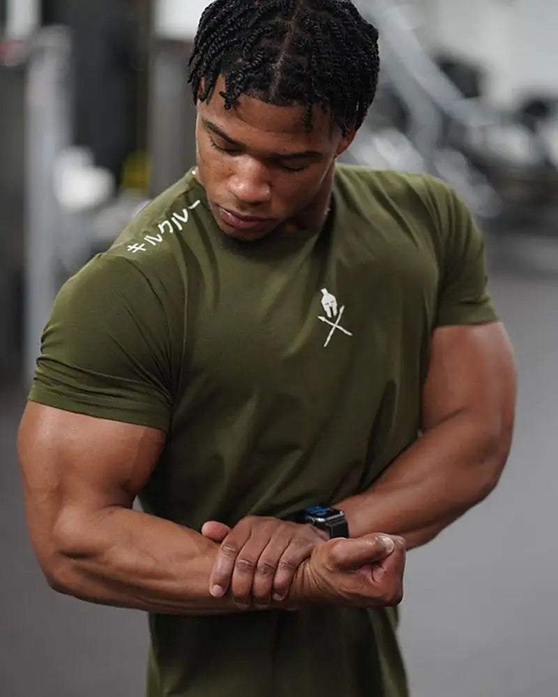 Athletic model in olive green t-shirt with brand logo checking smartwatch in gym setting