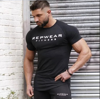 Athletic model wearing black REPWEAR FITNESS t-shirt poses against metal shutter, showing muscular physique