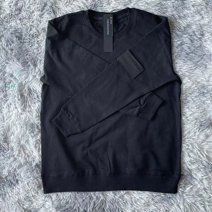 Black cotton sweatshirt with round neckline and black arm patch, displayed on plush gray fur background