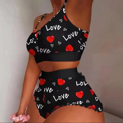 Black two-piece loungewear with "Love" text and red heart pattern, consisting of crop top and high-waist shorts