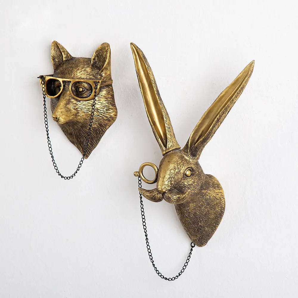 Brass-colored wolf and rabbit wall mounts with glasses and a monocle