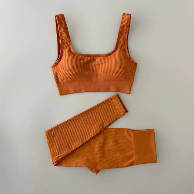Bright orange ribbed workout set with sports bra top and high-waisted shorts on light neutral background