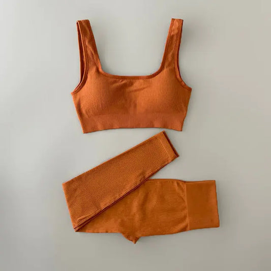 Bright orange ribbed workout set with sports bra top and high-waisted shorts on light neutral background