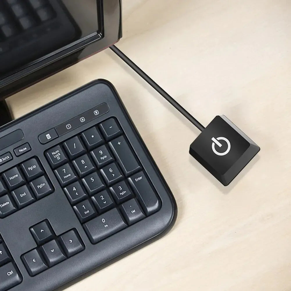 Close-up of a black computer keyboard with a numeric keypad and a connected black power button featuring a white power symbol.