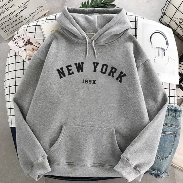 Gray melange New York pullover with black lettering and 199X text, displayed on grid pattern paper