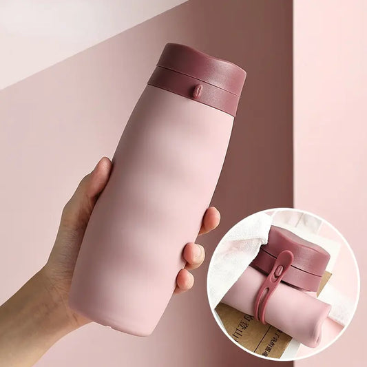 Hand holding pink water bottle with burgundy cap and strap; inset shows bottle folded in half.