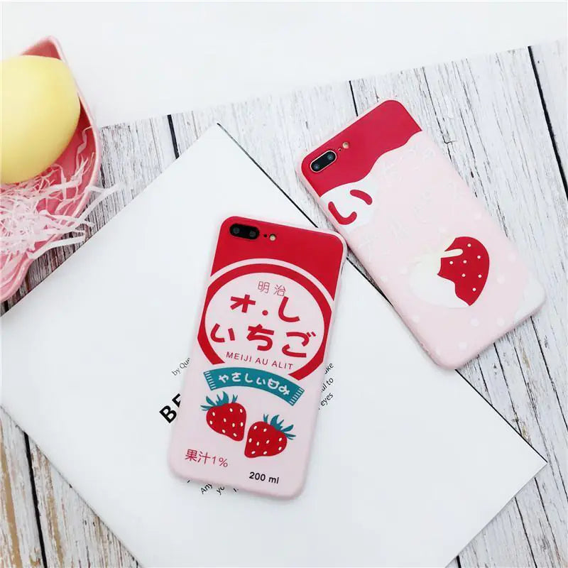 Japanese strawberry milk phone cases with red and pink designs on whitewashed wooden background