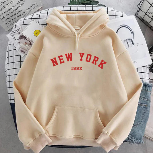 Khaki-colored New York hoodie with red lettering and 199X text, styled on grid background pattern