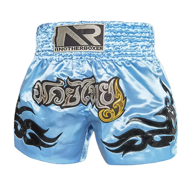 Light blue satin Muay Thai shorts with AnotherBoxer logo, silver Thai text and black tribal patterns
