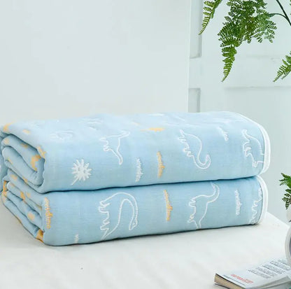 Light blue throw blanket with white animal outlines and yellow accents folded on table.