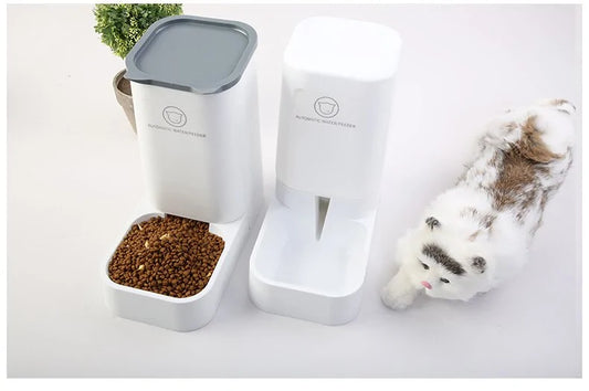 Modern white pet feeding station with automatic food and water dispensers next to a spotted white cat