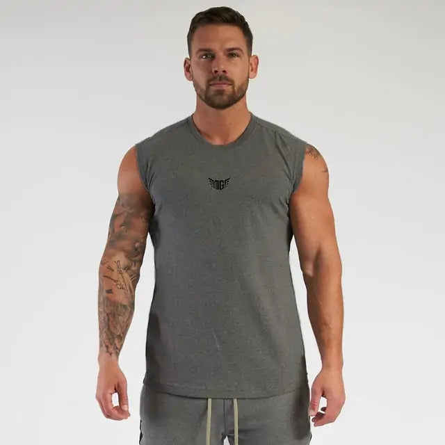 Muscular man wearing gray sleeveless workout shirt with wing emblem, full sleeve tattoo, on white background