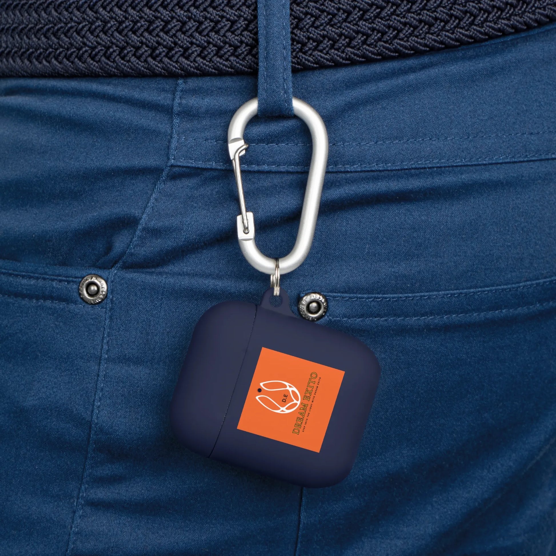 Navy blue AirPods case with orange design hangs from a carabiner on a blue belt loop