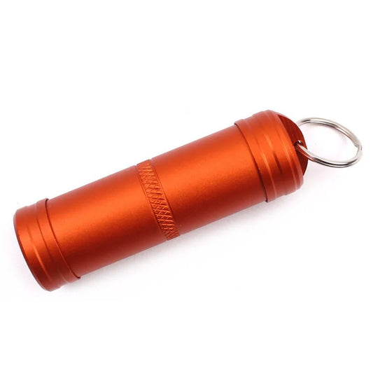 Orange metallic pill container with keyring attachment, cylindrical shape with textured grip.