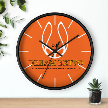 Orange wall clock with black frame, featuring a white flame logo and the words "DREAM EXITO.