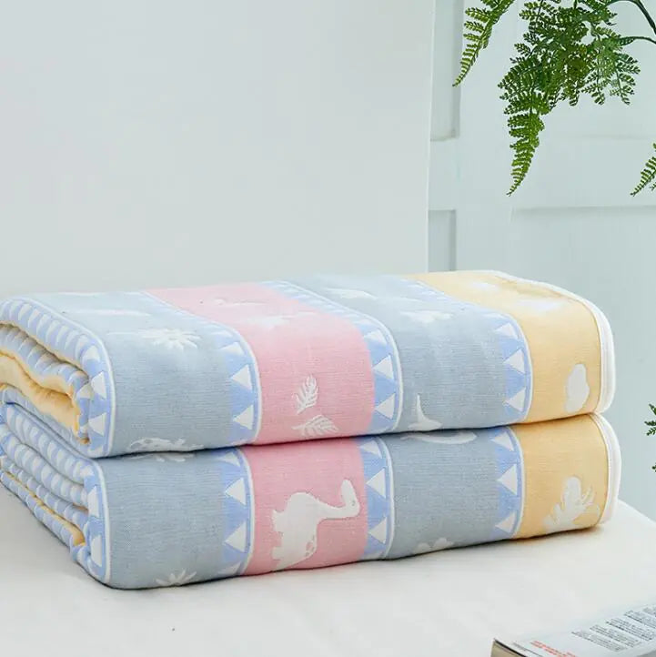 Pastel blanket with animal silhouettes in blue, pink, and yellow panels stacked on white surface.