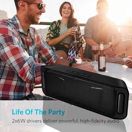 People enjoying a sunny gathering with a black portable speaker on a table.