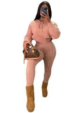 Person in pink cable-knit loungewear set with brown boots and designer handbag taking mirror selfie 