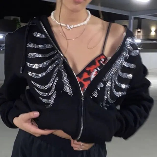 Person wearing black zip-up jacket with crystal ribcage design, pearl necklace, and red undergarment