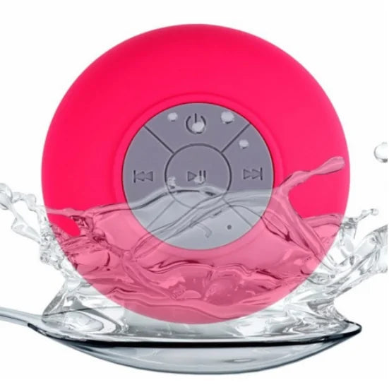 Pink waterproof Bluetooth speaker with control buttons, surrounded by splashing water.