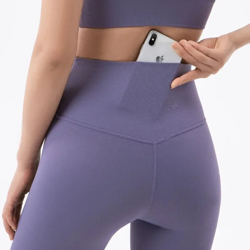 Purple workout leggings with high waistband pocket holding phone, shown from behind