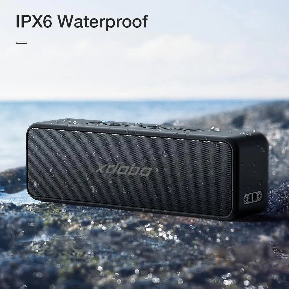 The Xdobo speaker with water droplets on its surface against a blurred nature background, demonstrating its IPX6 waterproof rating.
