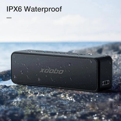 The Xdobo speaker with water droplets on its surface against a blurred nature background, demonstrating its IPX6 waterproof rating.