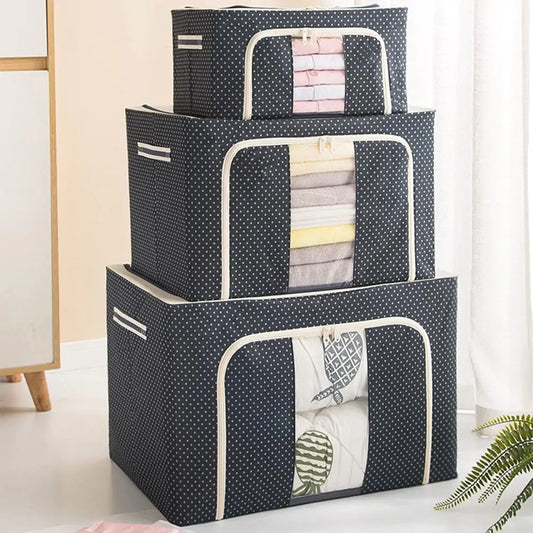 Three stacked storage boxes in navy polka-dot fabric with clear windows showing folded linens, white trim detail