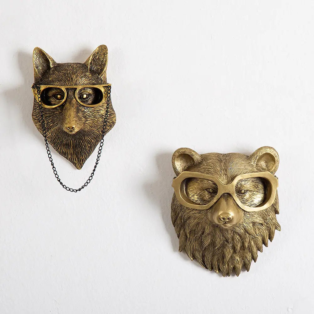 Two bronze animal head wall ornaments wearing glasses