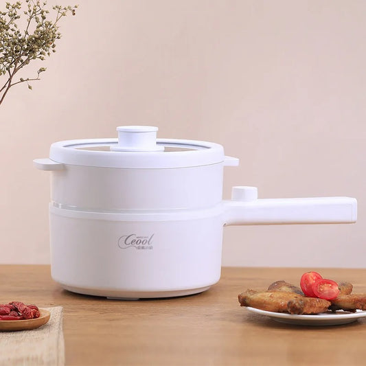 White ceramic electric cooking pot with wooden handle and food on wooden table