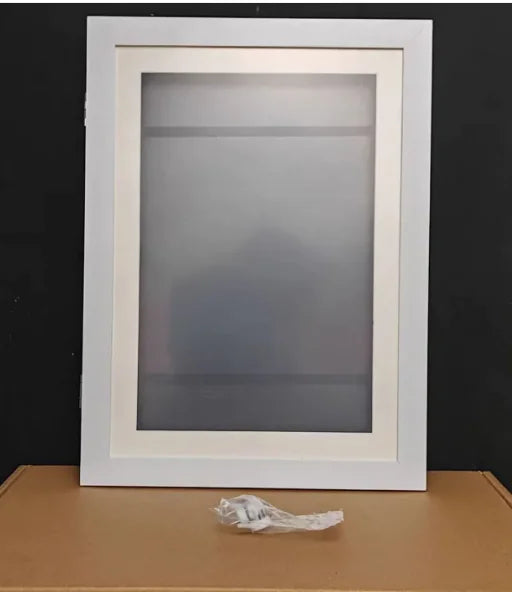 White picture frame standing on brown surface with cord visible below, frame contains frosted glass panel