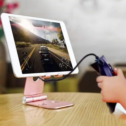 White tablet on pink stand displaying racing game with controller held by person's hand