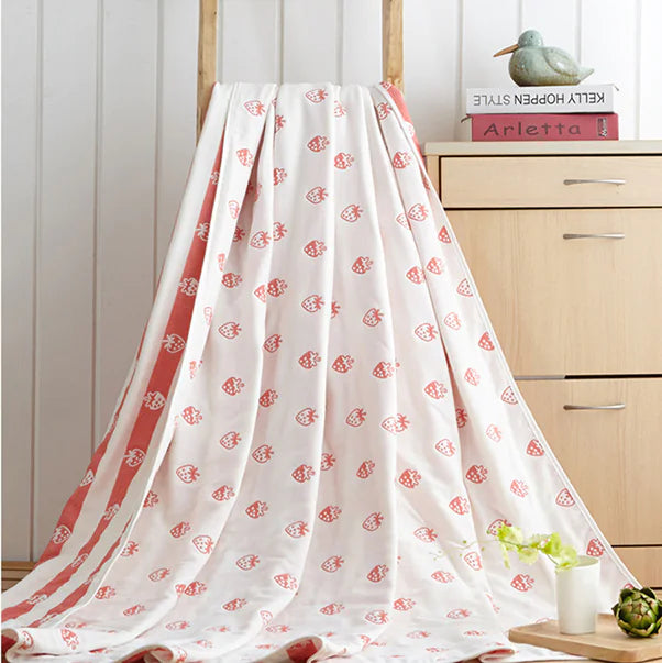 White throw blanket with small coral fish patterns draped over wooden rack.