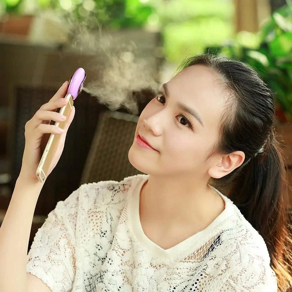 Woman in white lace top enjoying mist from pink portable humidifier in garden setting.