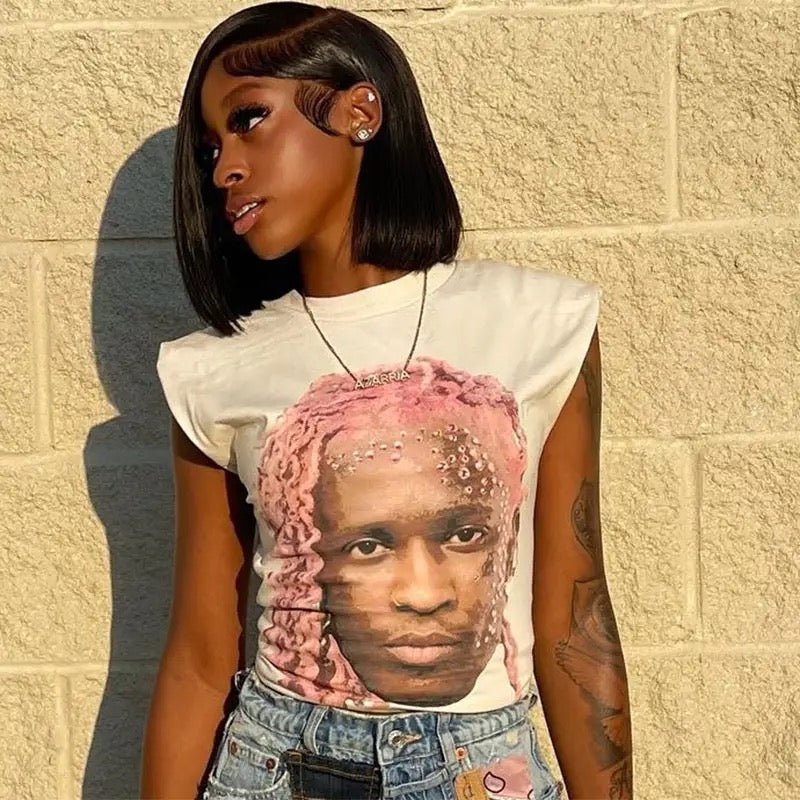Woman with short black hair and a white graphic tee featuring a portrait of a person with pink hair.
